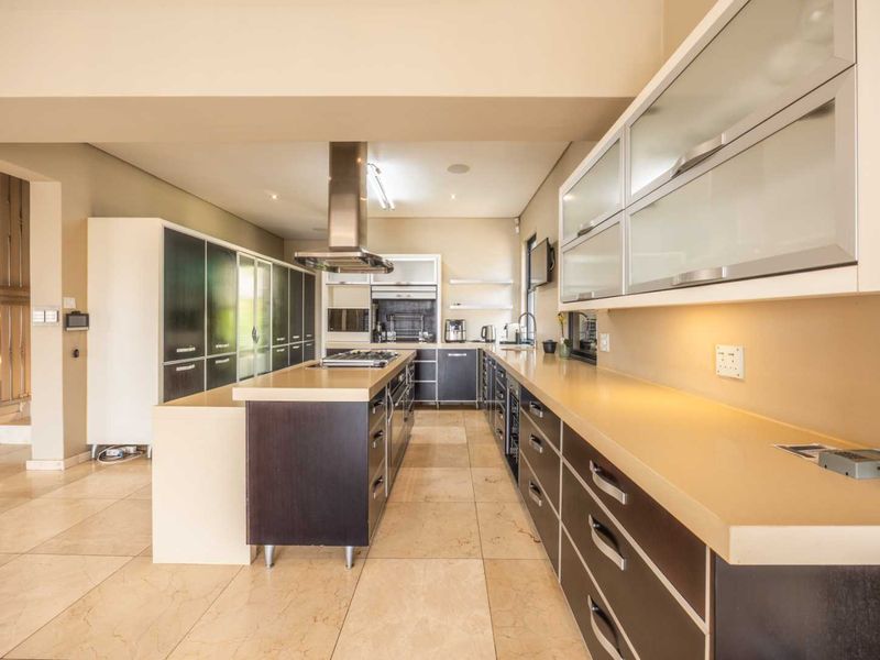 Modern kitchen featuring a central island, stone countertops, built-in cabinetry, stainless steel extractor fan, and tiled flooring.