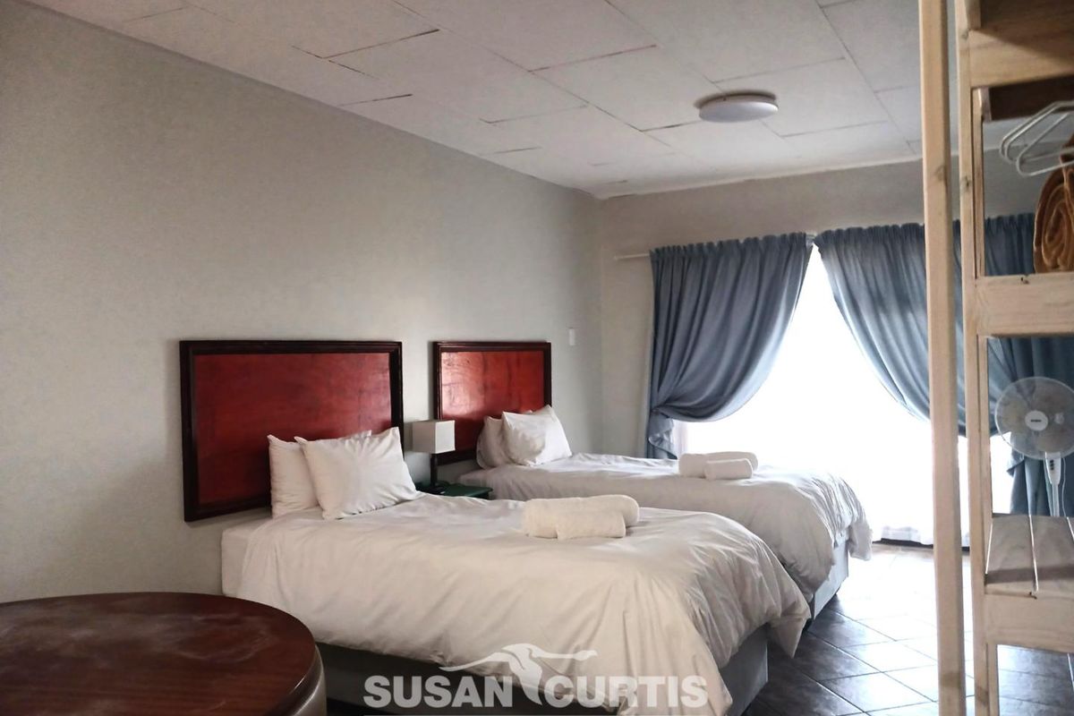A twin bedroom featuring tiled flooring and large windows with curtains, providing a functional guest accommodation space.