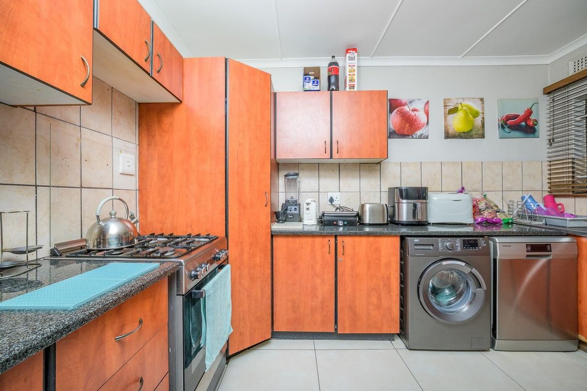 A functional kitchen featuring laminate cabinetry, granite countertops, a gas stove, and integrated laundry and dishwasher appliances with a tiled backsplash.