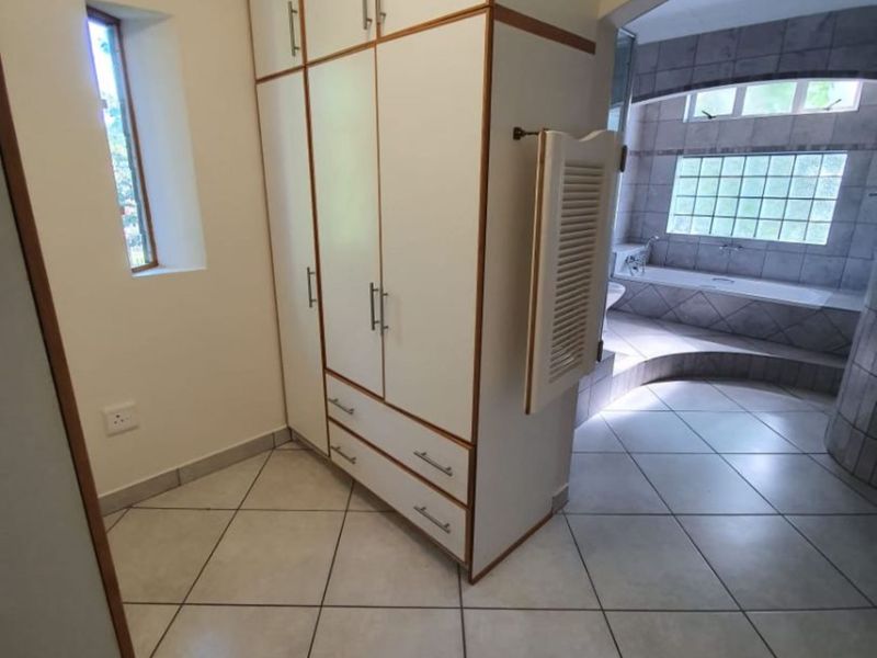 A bathroom area featuring built-in cabinetry, tiled flooring, and a sunken bathtub with a glass block window feature.
