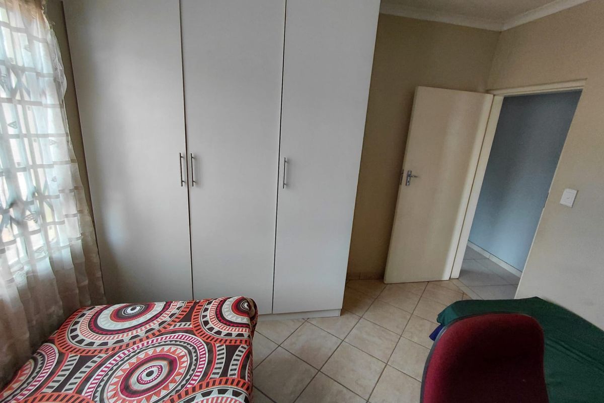 A bedroom featuring built-in cupboards and tiled flooring, providing a functional space with neutral wall tones.