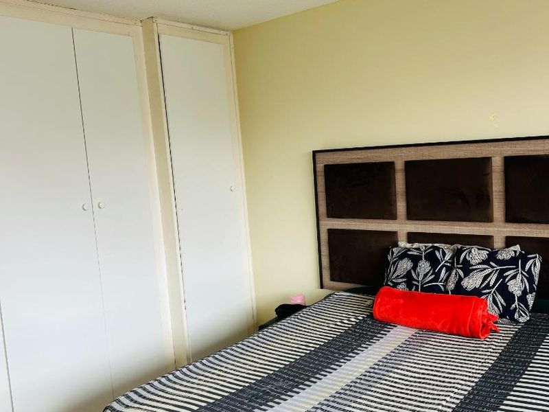 A functional bedroom featuring built-in cupboards, tiled flooring, and a standard ceiling light fixture, offering a neutral base for potential updates.