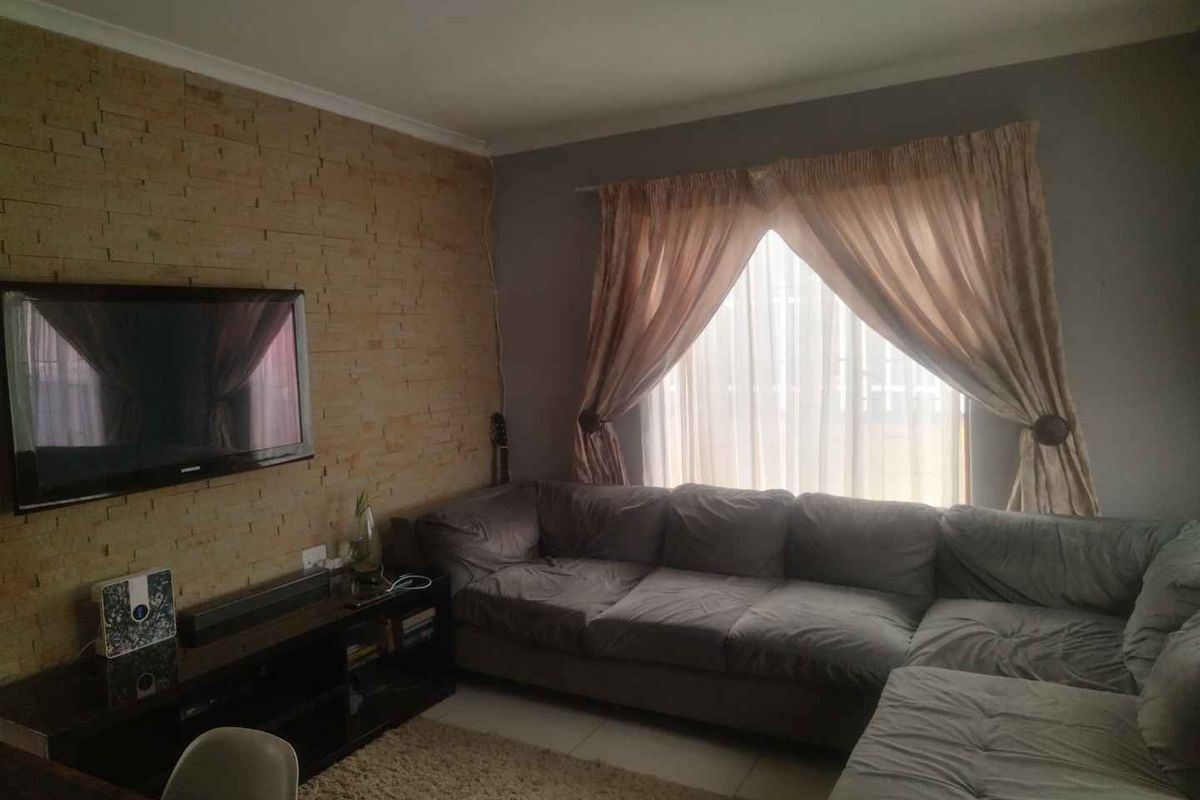 A comfortable living room featuring a textured stone feature wall and tiled flooring, providing a cozy space for relaxation.