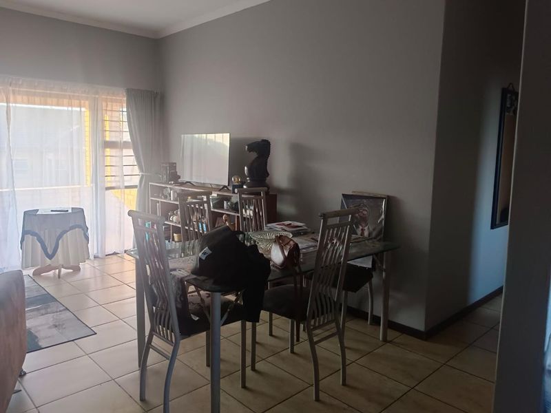A living area featuring tiled flooring and a sliding glass door with security gate, providing access to the exterior.