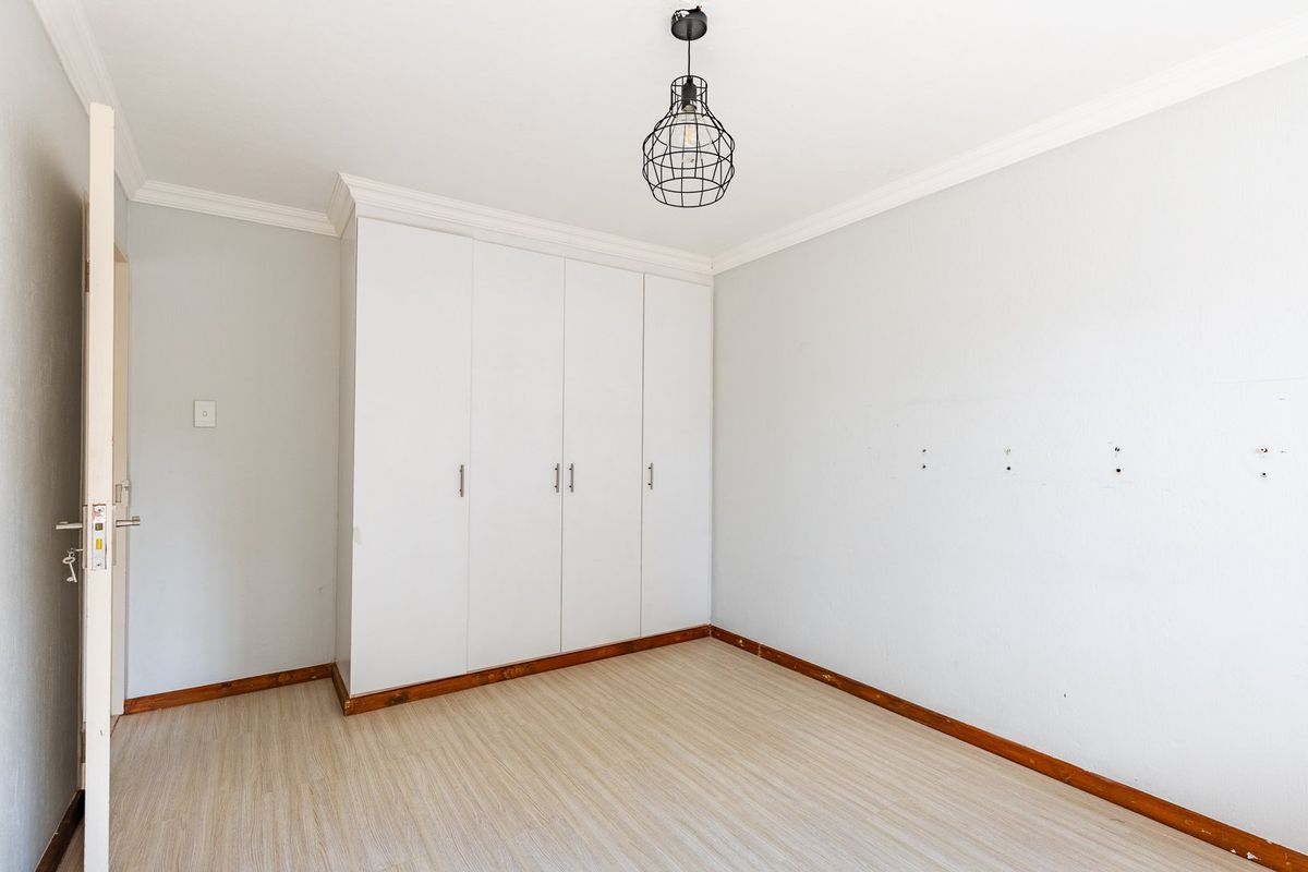 An empty bedroom featuring built-in cupboards, laminate flooring, and coving, providing a clean and neutral space ready for personalization.