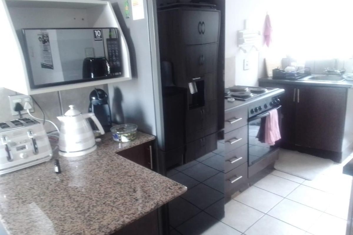 A functional kitchen featuring granite countertops, dark cabinetry, a built-in oven with hob, and tiled flooring.