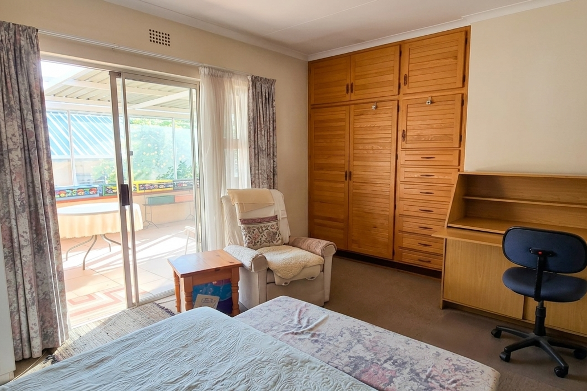 A bedroom featuring built-in wooden cabinetry and sliding glass doors that provide direct access to an outdoor patio area.
