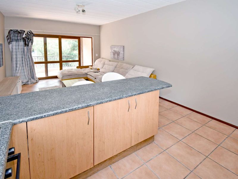 Open plan living area featuring a kitchen island with granite countertops, tiled flooring, and large sliding doors leading to an outdoor space.