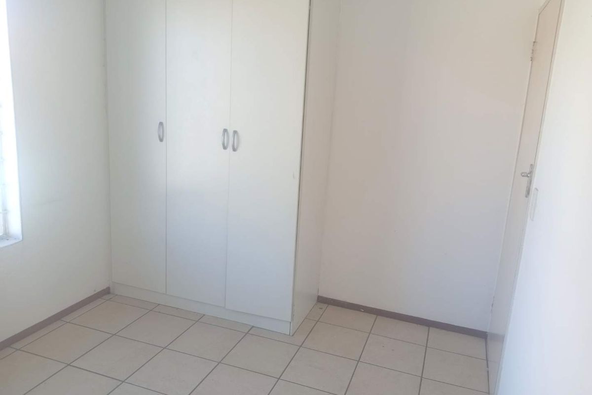 A clean, empty bedroom featuring neutral tiled flooring and white built-in cupboards, offering a blank canvas for personalization.