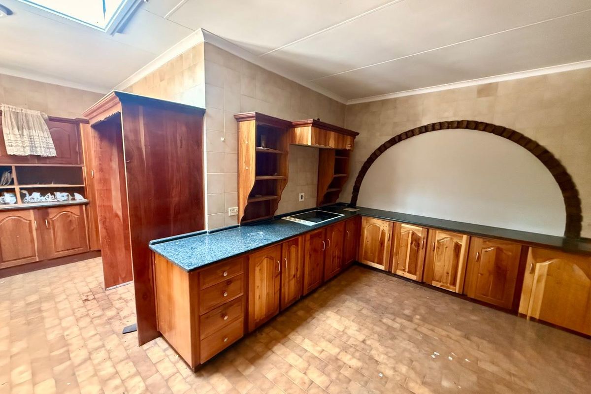 Spacious kitchen featuring traditional wooden cabinetry, laminate countertops, a built-in hob, and a unique decorative brick arch feature with a skylight above.