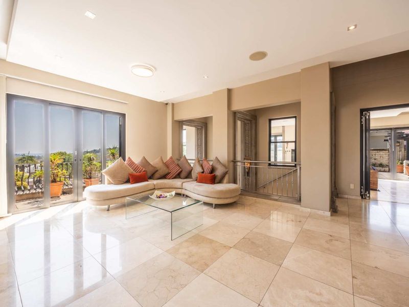 Spacious living area featuring polished stone tile flooring, recessed lighting, and large sliding glass doors that open to an outdoor balcony.
