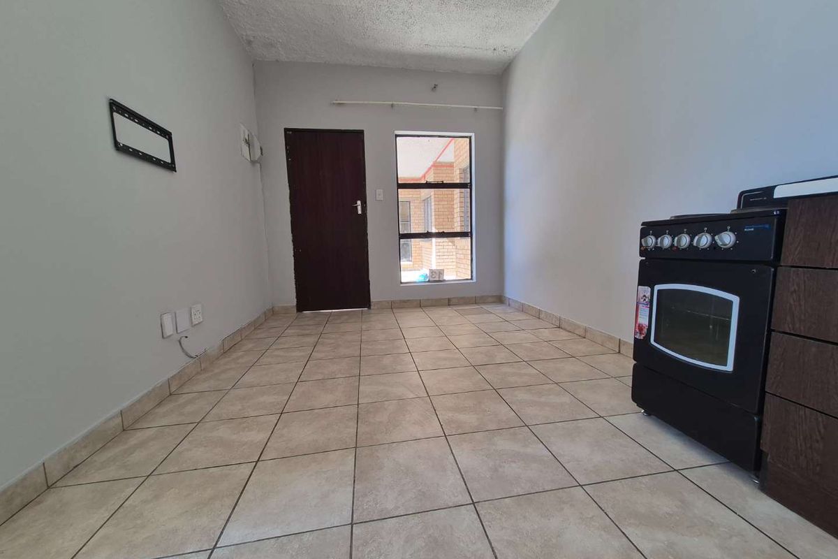 A compact, empty kitchen area featuring tiled flooring, a built-in oven, and a textured ceiling, offering a blank canvas for renovation.