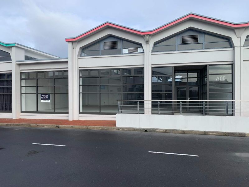 Modern retail storefront featuring large glass windows, a metal-framed entrance, and a clean concrete facade, suitable for a variety of commercial business uses.