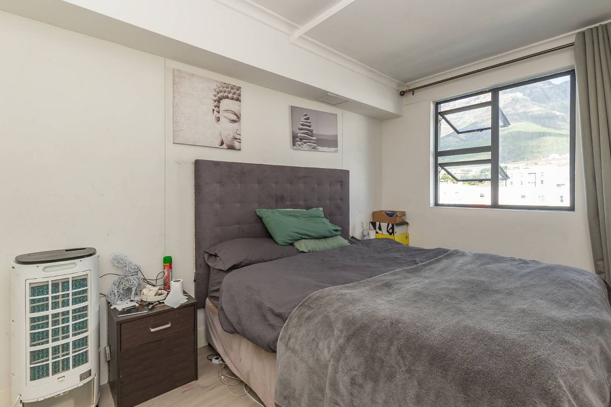 A functional bedroom featuring a window with mountain views, neutral wall finishes, and standard flooring.