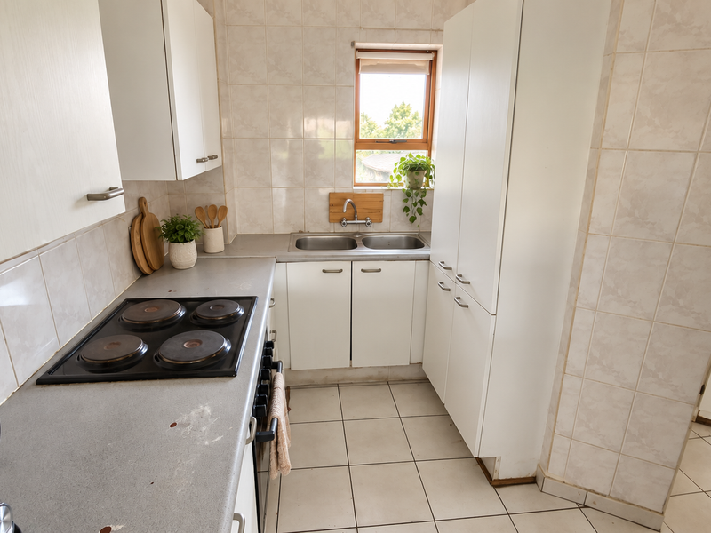 A functional kitchen featuring white cabinetry, a tiled splashback, an electric hob, and a double sink with a window view.