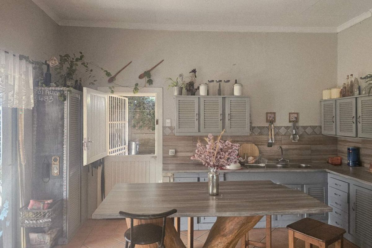 A rustic kitchen featuring grey cabinetry, tiled backsplash, a double sink, and a unique central island with a natural wood base.