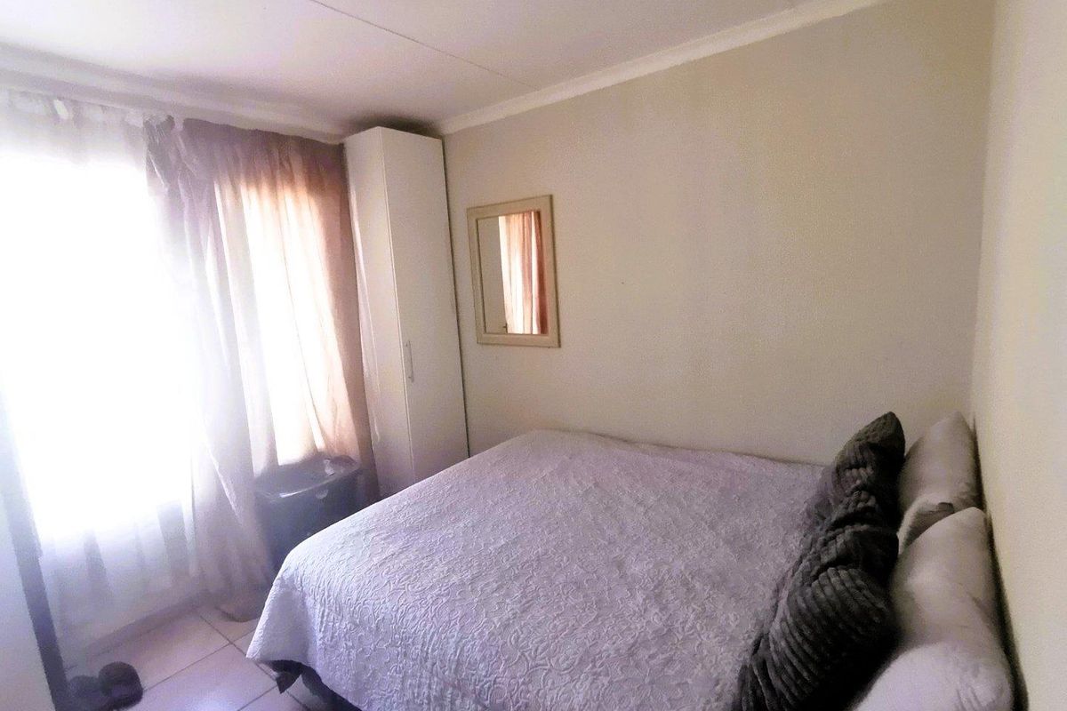A functional bedroom featuring tiled flooring, a built-in wardrobe, and natural light through the window.