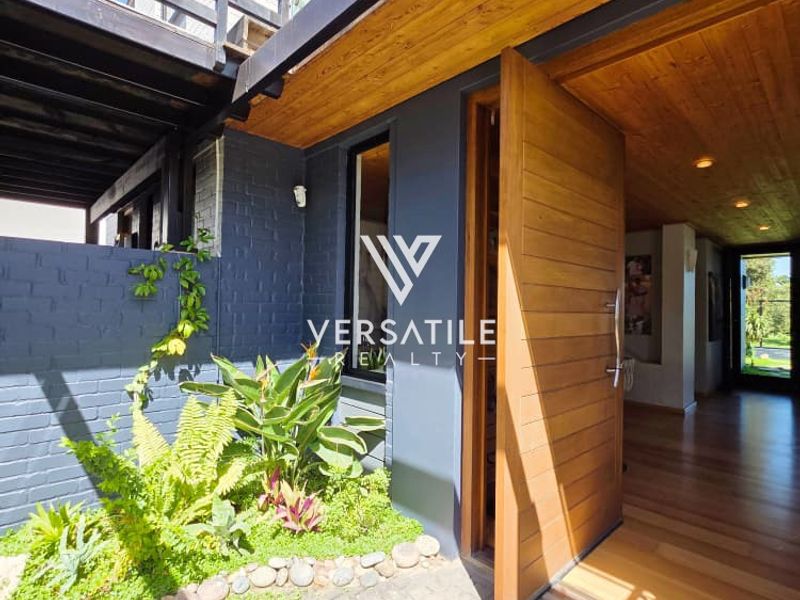 Modern entrance featuring a large timber pivot door, timber-lined ceiling, and seamless transition to the interior with high-quality finishes and a landscaped courtyard.