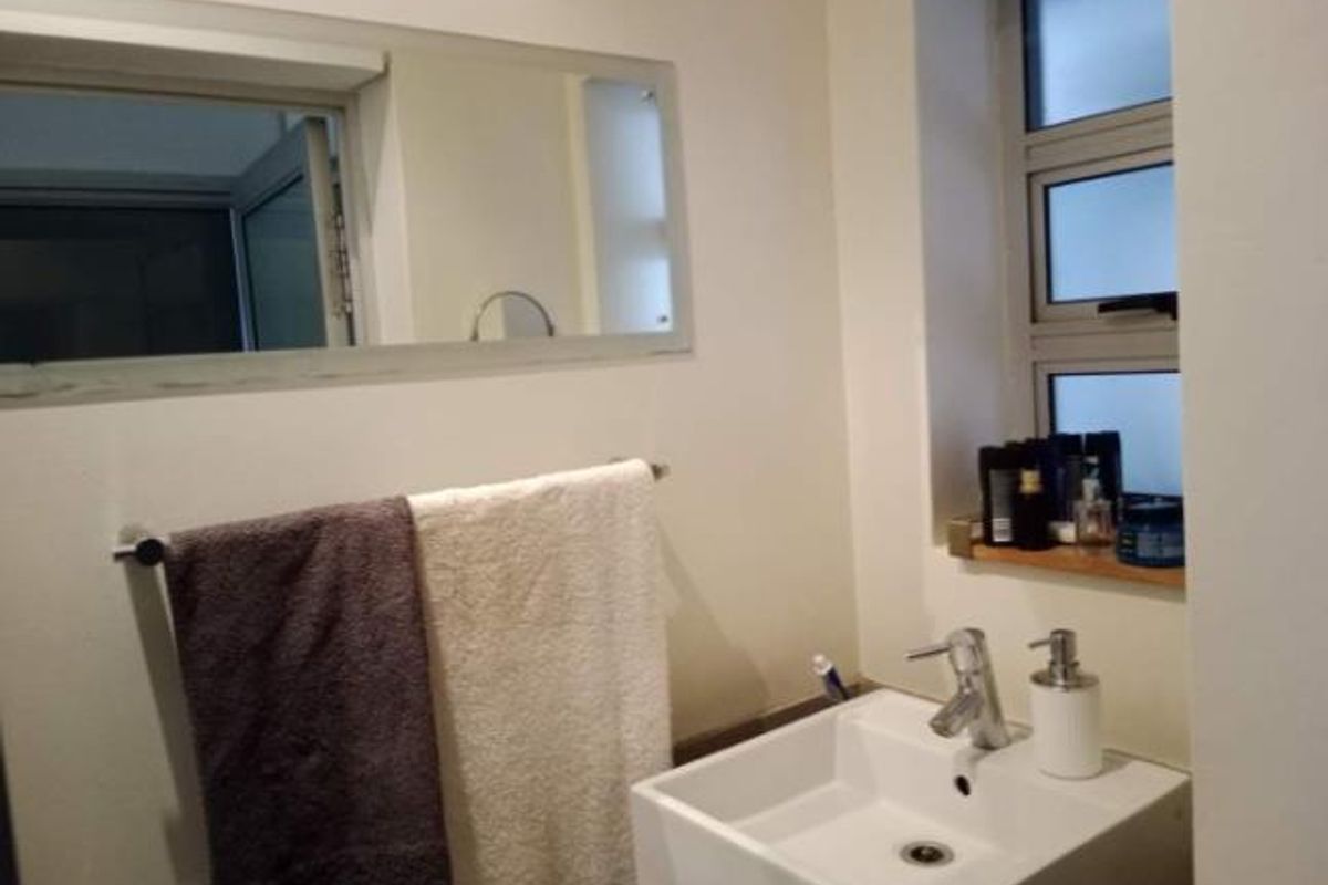 A functional bathroom featuring a modern vessel sink with a chrome mixer tap, a wall-mounted mirror, and an aluminium-framed window.