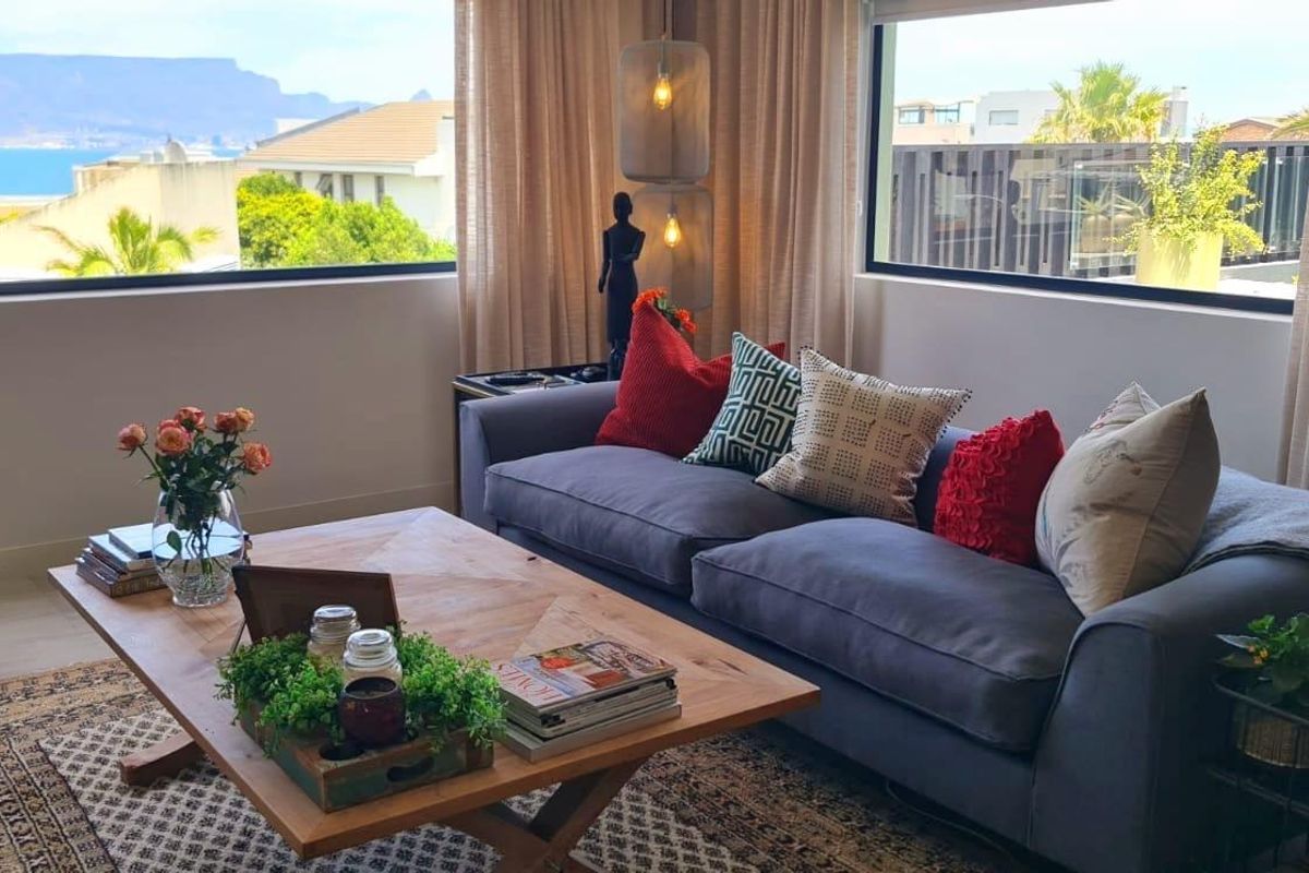 A bright living room featuring large windows that frame expansive mountain and coastal views, creating a light-filled and inviting atmosphere.