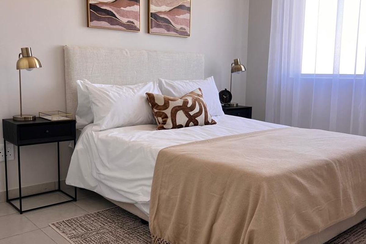 A well-maintained bedroom featuring neutral wall tones, tiled flooring, and a vaulted ceiling, providing a bright and comfortable living space.