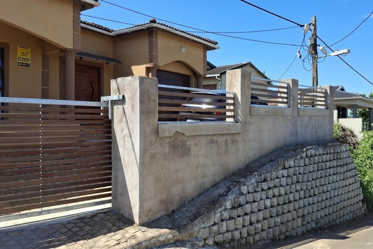 Front exterior view showing a sliding gate, boundary wall with metal inserts, and a retaining wall structure.