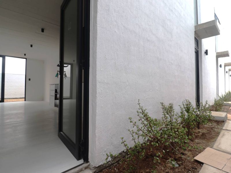 Modern open-plan living space with sleek black-framed glass doors, recessed lighting, and a clean, minimalist interior aesthetic.