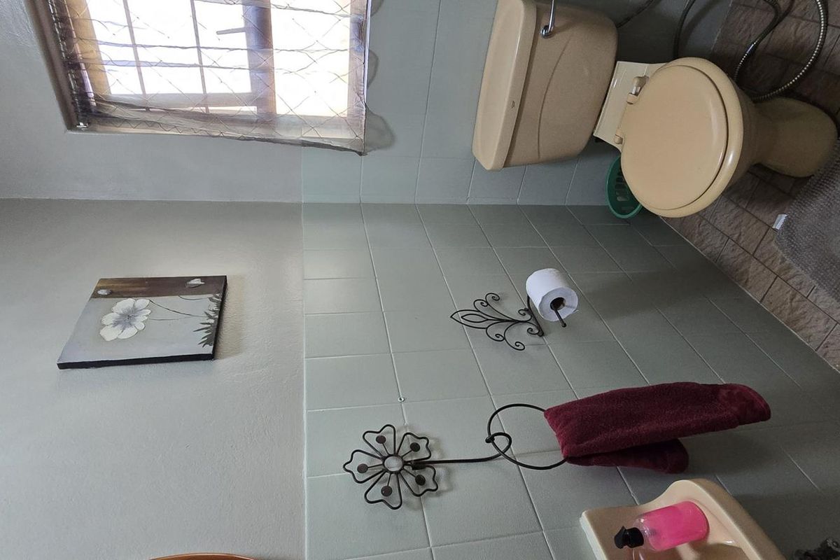 A functional bathroom featuring tiled walls and flooring with dated sanitaryware, offering potential for a modern renovation.