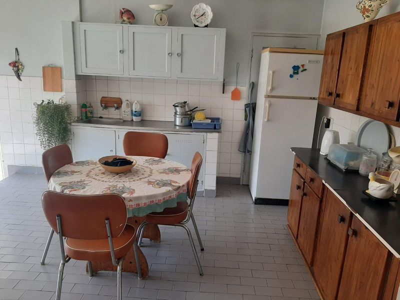 A functional kitchen featuring traditional wooden cabinetry, tiled backsplash, and tiled flooring, offering a dated aesthetic with potential for modern renovation.