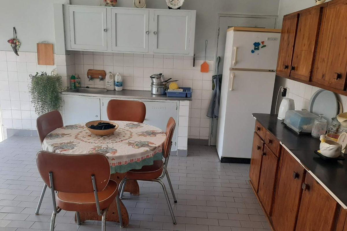 A functional kitchen featuring traditional wooden cabinetry, tiled backsplash, and tiled flooring, offering a dated aesthetic with potential for modern renovation.