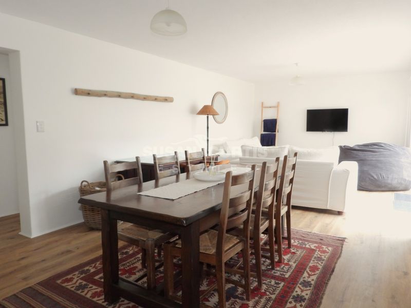 An open-plan living and dining area featuring laminate flooring, neutral walls, and integrated lighting, providing a versatile space for relaxation and entertaining.
