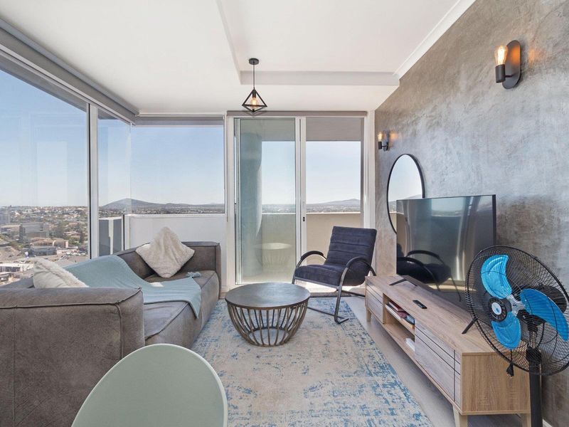 Modern living room featuring a textured feature wall, floor-to-ceiling windows with expansive city views, and direct access to a private balcony.