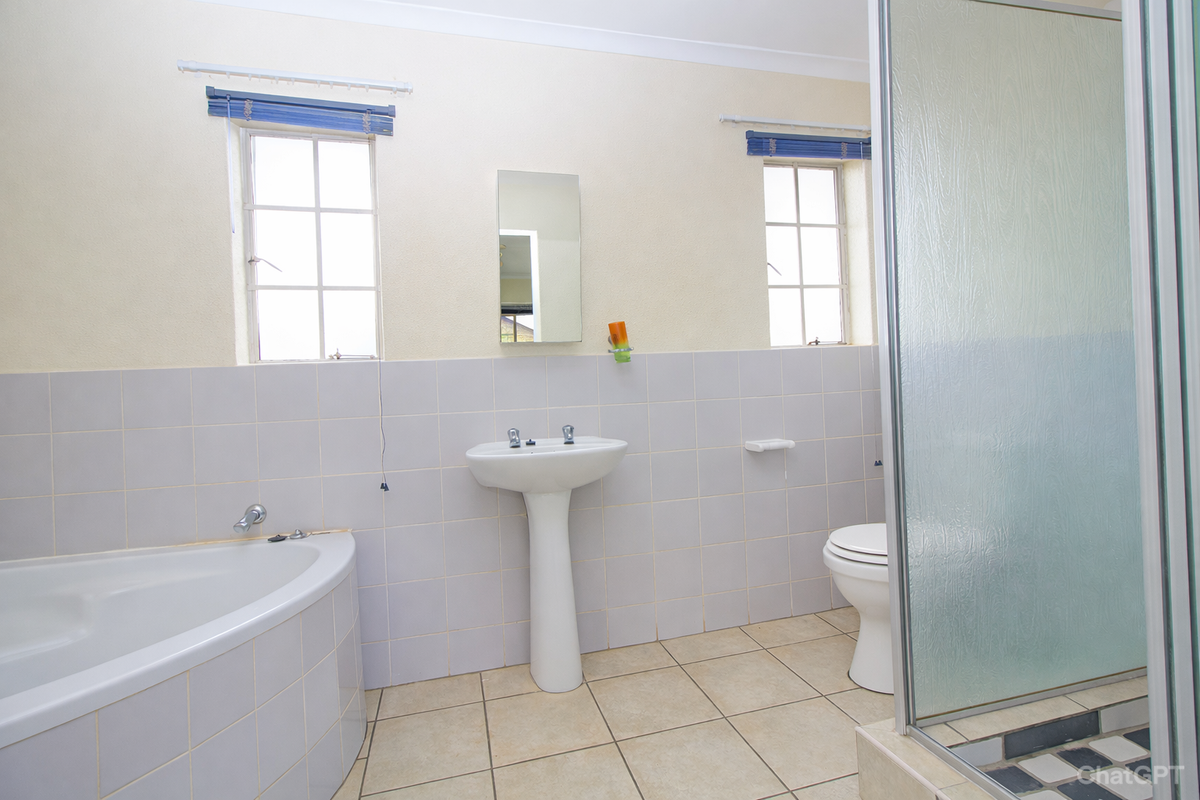 A functional bathroom featuring a corner bathtub, pedestal basin, toilet, and a separate glass-enclosed shower stall with tiled flooring.