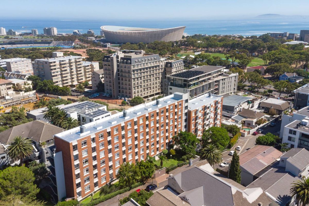 Aerial view of a multi-story brick apartment complex situated in an urban neighborhood with proximity to the stadium and coastline.