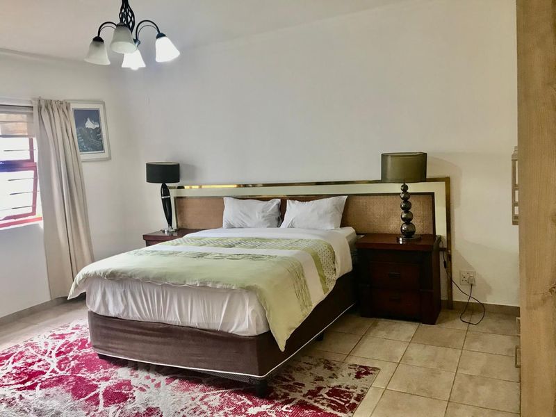 A well-lit bedroom featuring tiled flooring and a central ceiling light fixture, providing a functional and comfortable sleeping space.