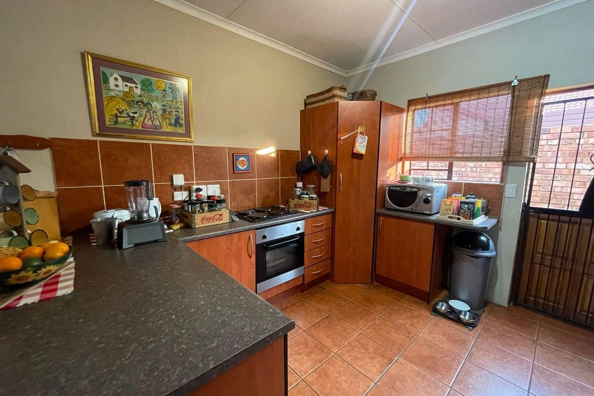 A functional kitchen featuring wood-finish cabinetry, tiled splashbacks, a built-in oven and hob, and direct access to an exterior area.