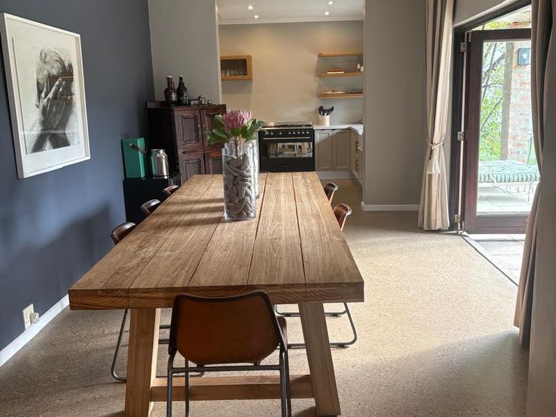 Open-plan dining area featuring polished concrete floors, recessed lighting, and direct access to an outdoor patio through glass french doors.