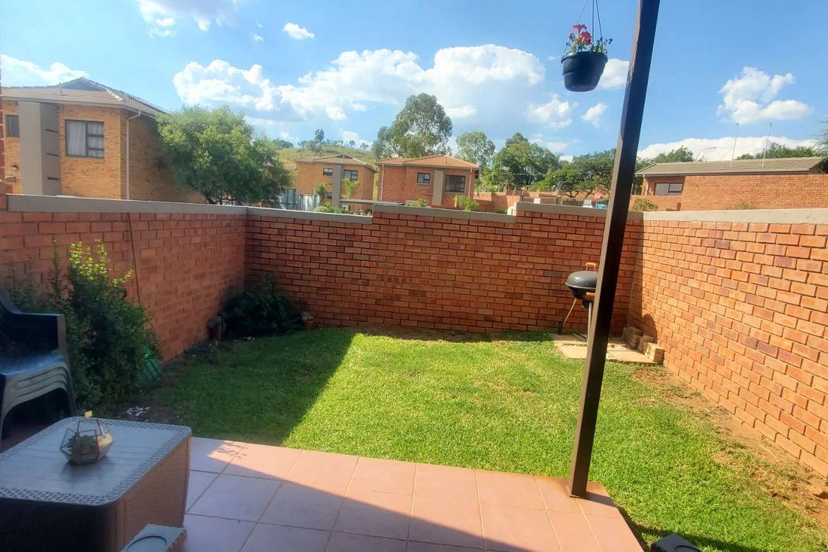 A private rear garden featuring a tiled patio area, enclosed by face-brick boundary walls, offering a low-maintenance outdoor space.