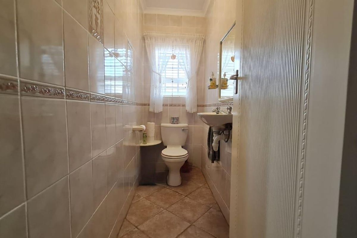 A compact guest bathroom featuring floor-to-ceiling wall tiles, a pedestal basin, and a standard toilet.