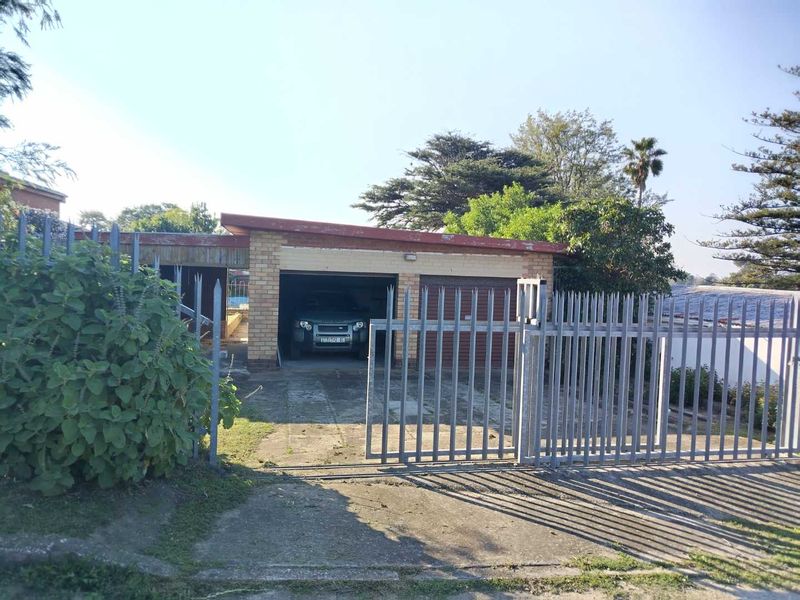 Front view of a residential property featuring a double garage, concrete driveway, and metal security fencing.