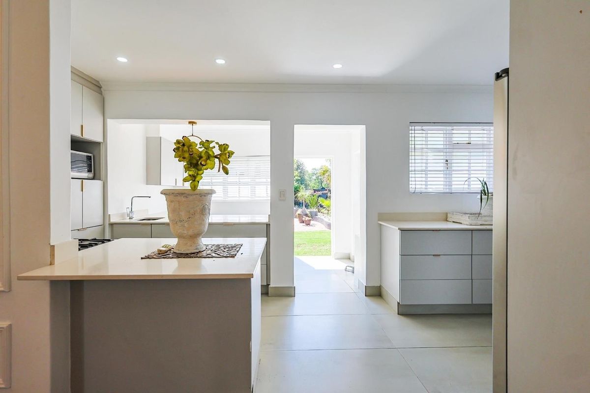 Modern kitchen featuring sleek cabinetry, stone countertops, recessed lighting, and a functional layout with direct access to the rear garden.
