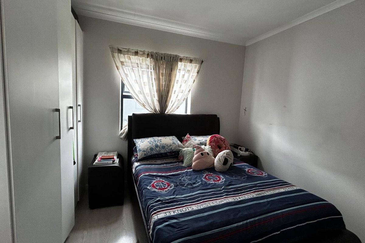 A functional bedroom featuring built-in white cabinetry and neutral flooring, providing a clean and practical living space.