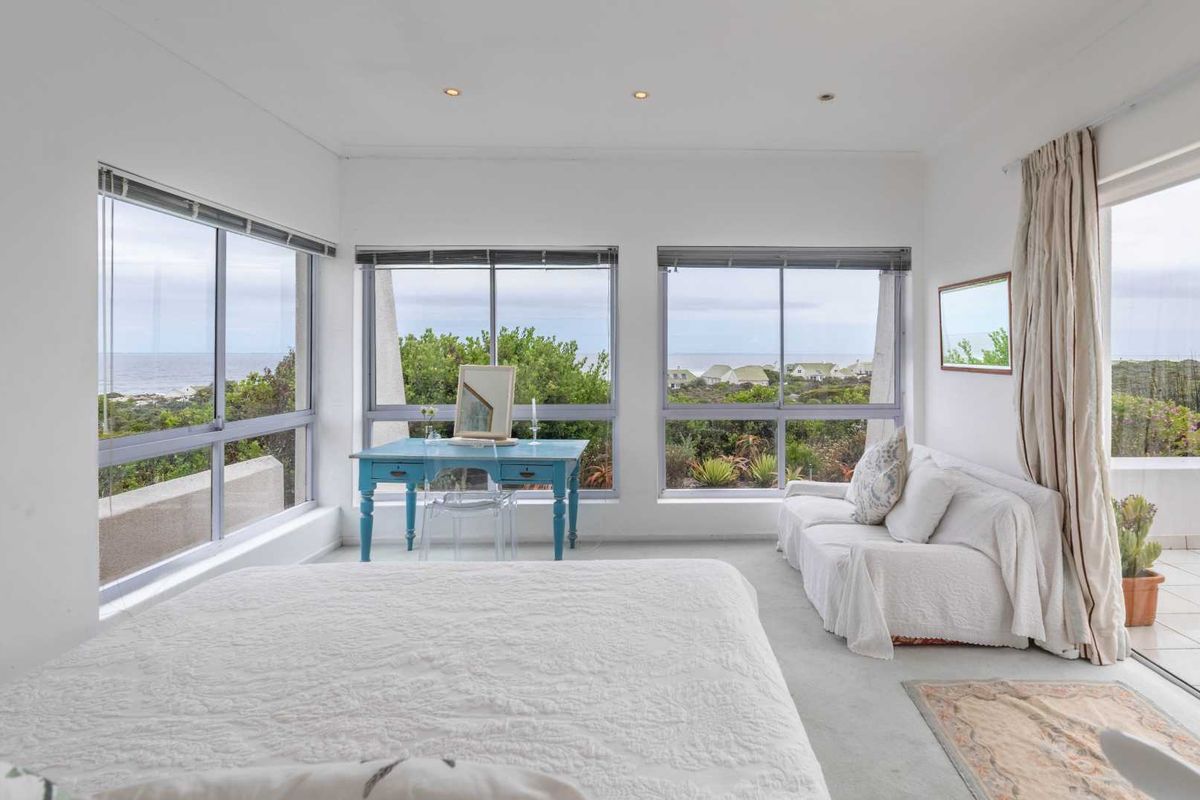 Bright bedroom featuring large windows with scenic coastal views and direct access to an outdoor patio area.