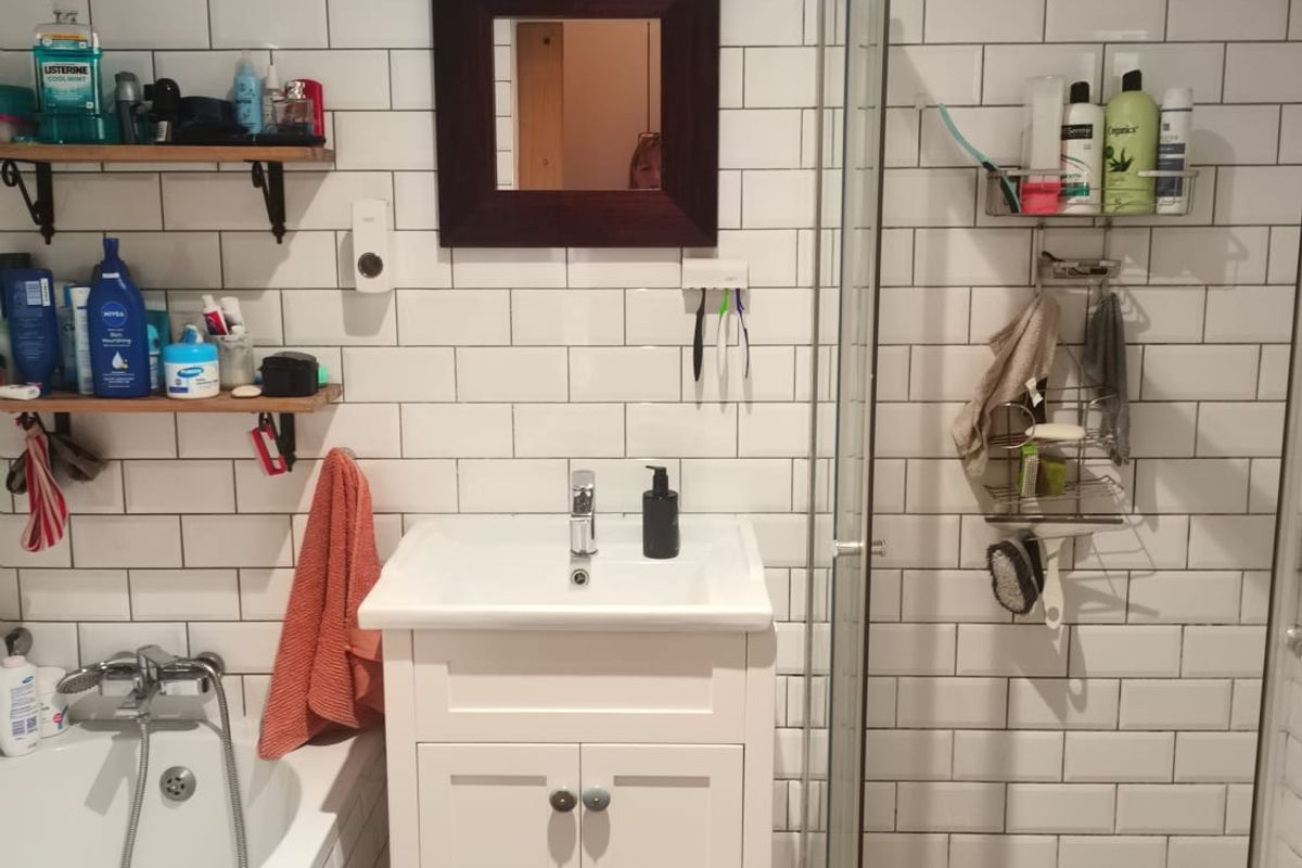 A functional bathroom featuring a white vanity, bathtub, and separate shower enclosure with classic subway tile wall finishes.