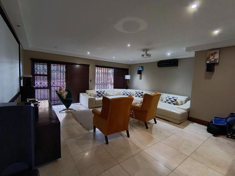 Spacious living room featuring tiled flooring, recessed lighting, split-system air conditioning, and integrated projector setup, ideal for a home cinema experience.