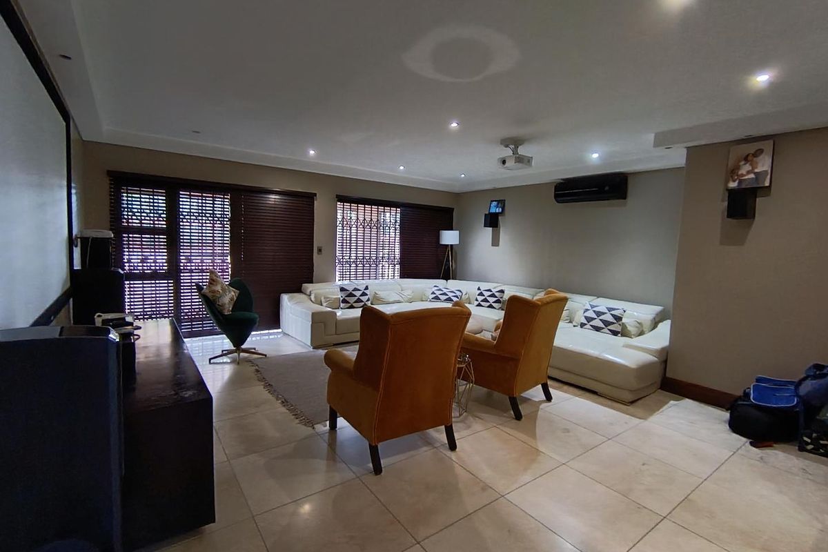 Spacious living room featuring tiled flooring, recessed lighting, split-system air conditioning, and integrated projector setup, ideal for a home cinema experience.
