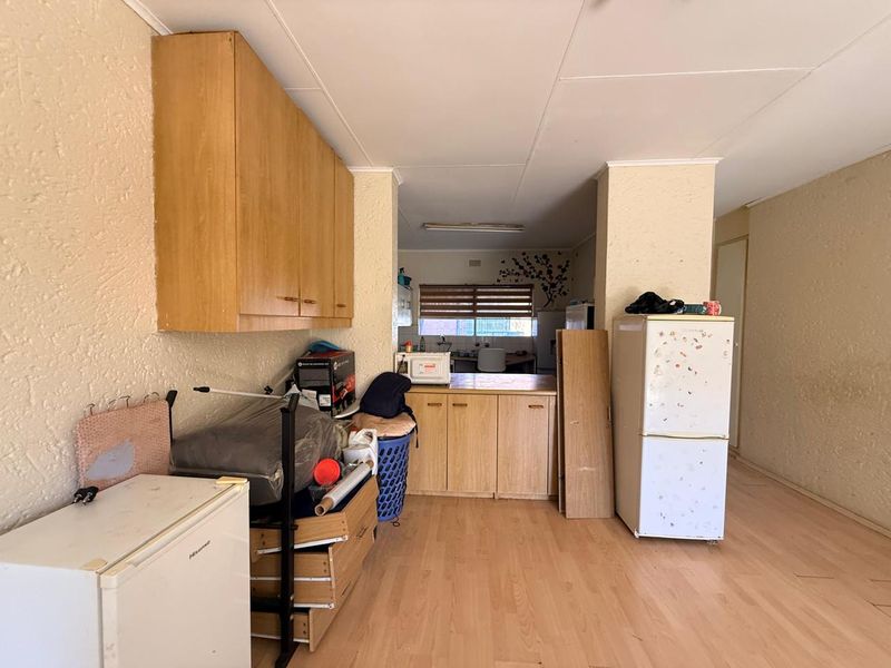 Open plan living and kitchen area featuring laminate flooring and dated built-in cabinetry, offering potential for modernization and renovation.