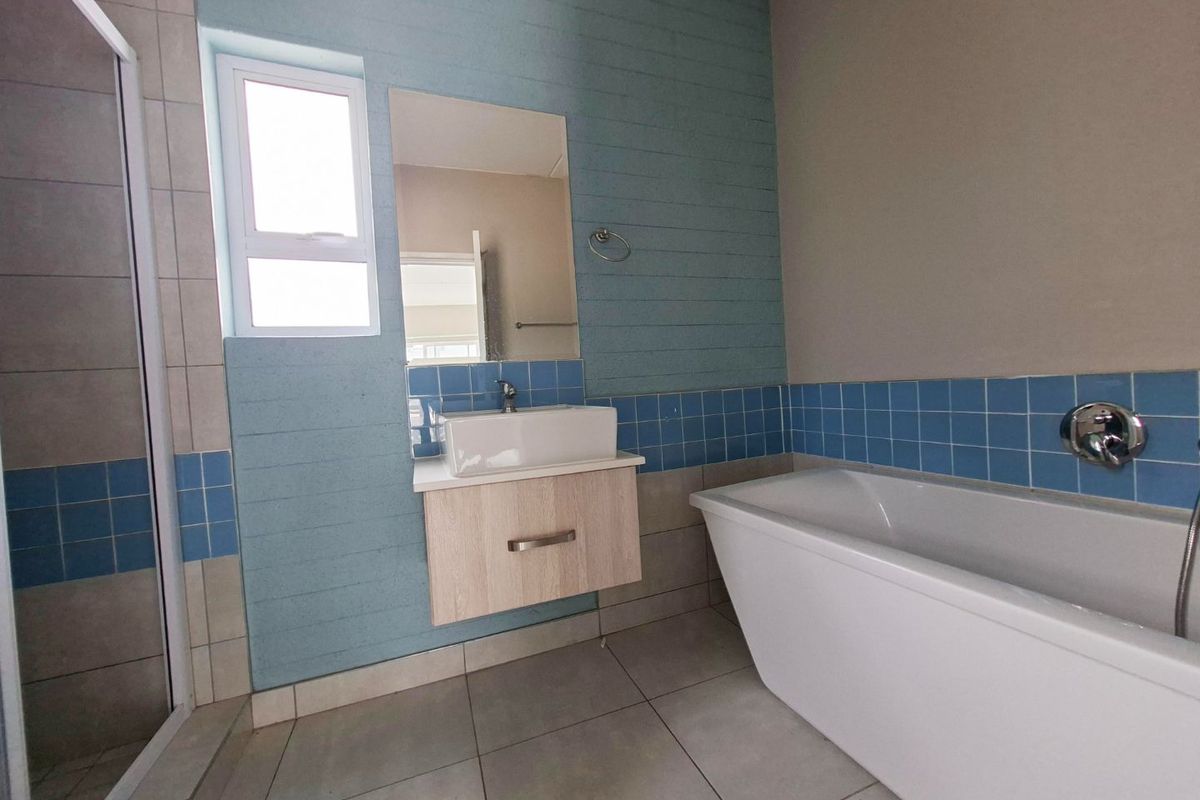Modern bathroom featuring a freestanding bathtub, a wall-mounted vanity with a vessel sink, a separate shower enclosure, and contemporary tiled finishes.