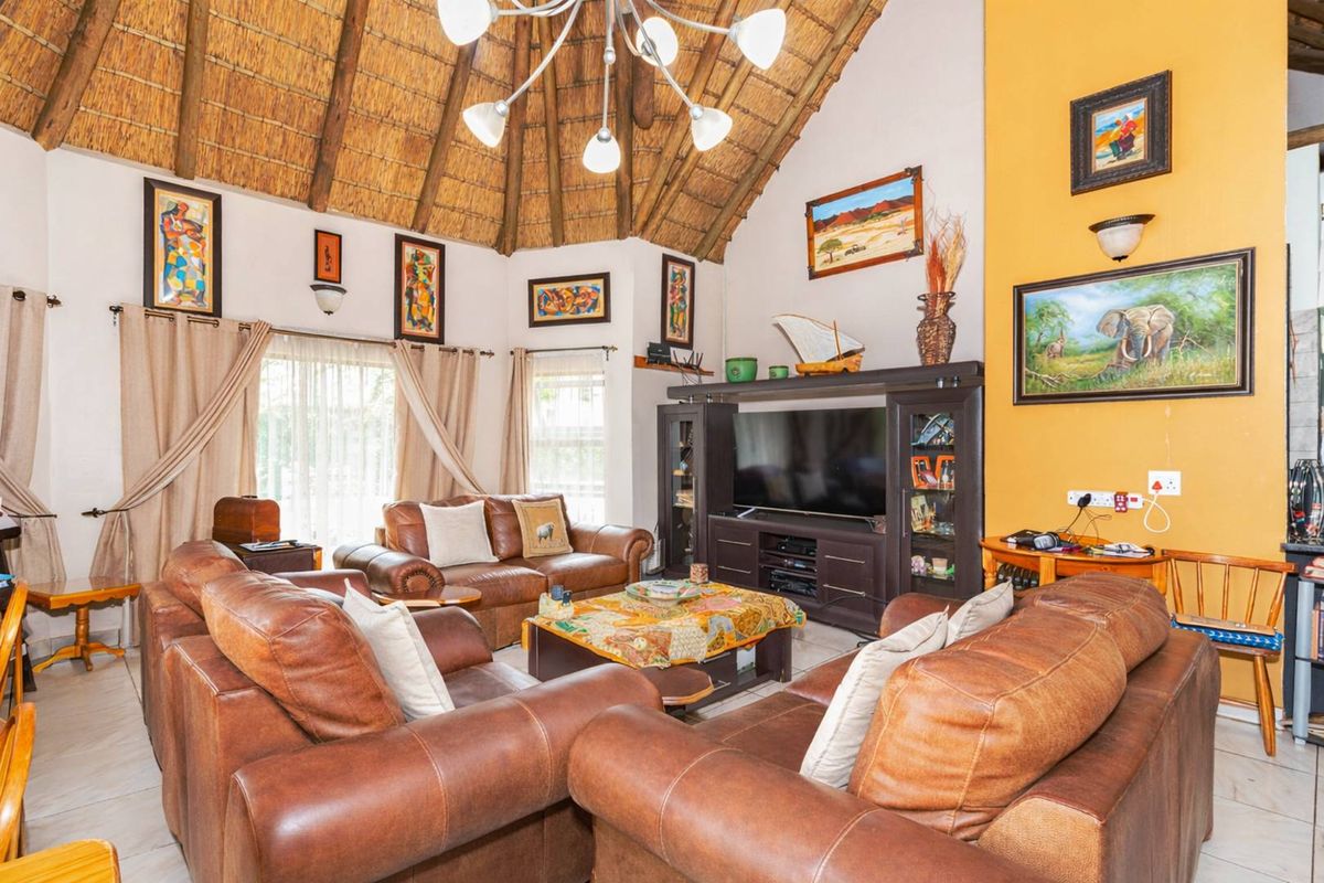 Spacious living room featuring a high vaulted thatched ceiling, tiled flooring, and large windows allowing for natural light.