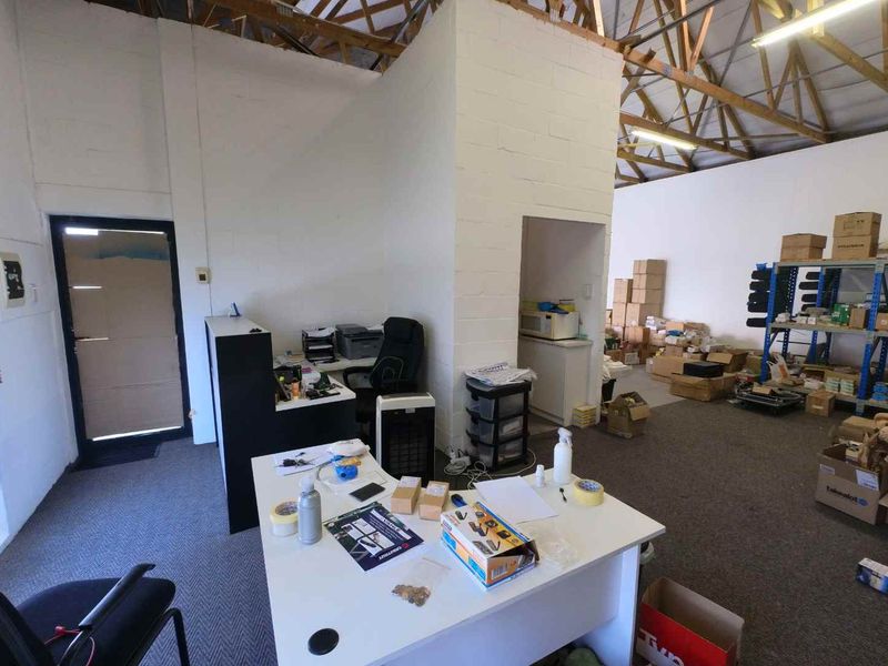 Industrial utility space featuring exposed timber roof trusses, blockwork walls, and carpeted flooring, suitable for storage or workshop use.